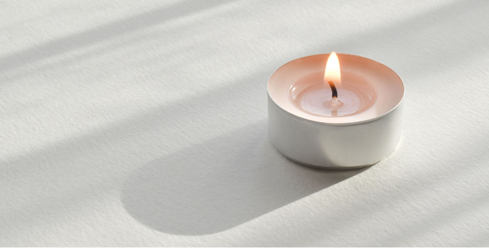 A soothing pink tea light resting on a peaceful, cream surface inviting the reader to imagine what Meditation and Mindfulness might feel like.